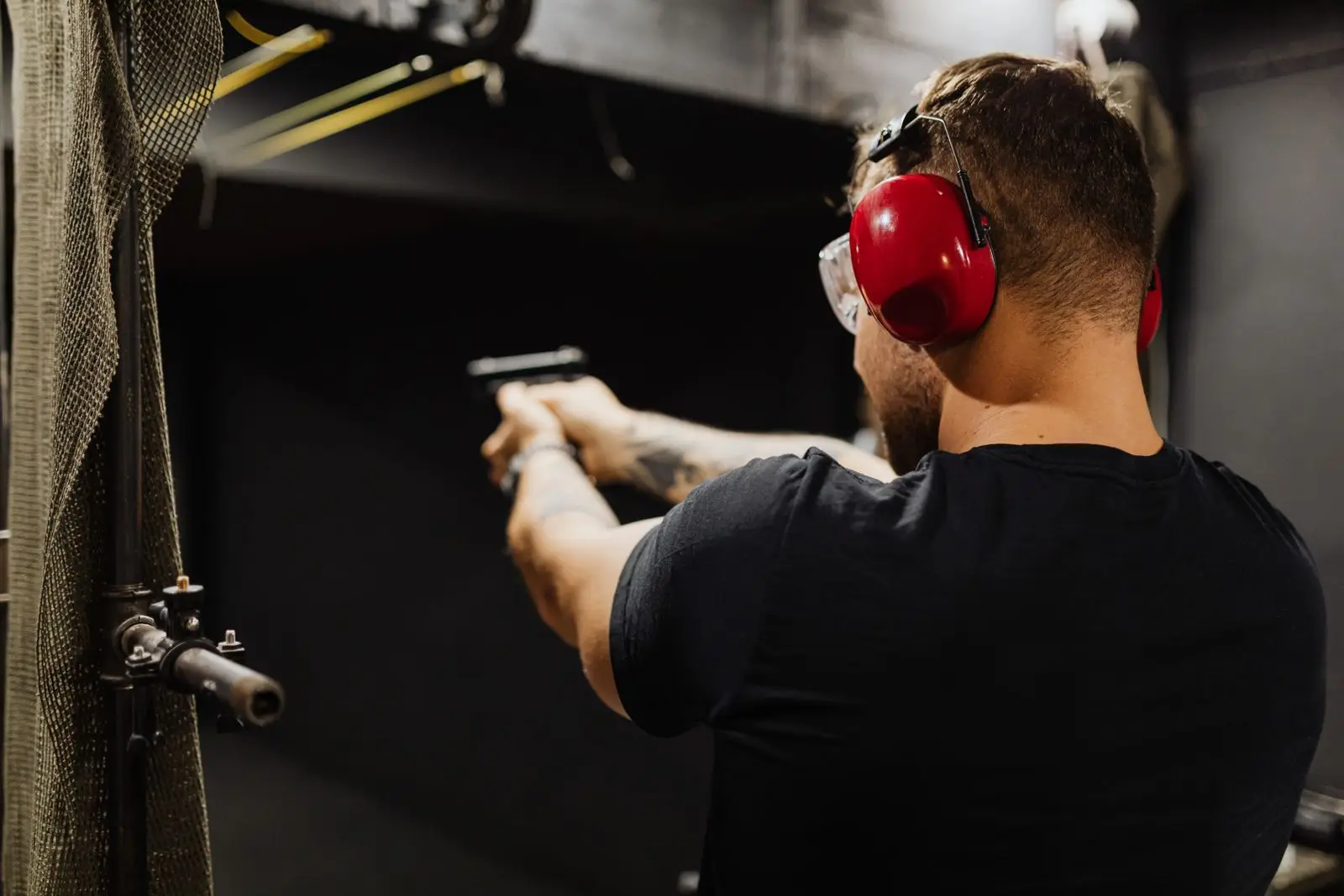 Man with ear protection practicing with a handgun at an indoor range